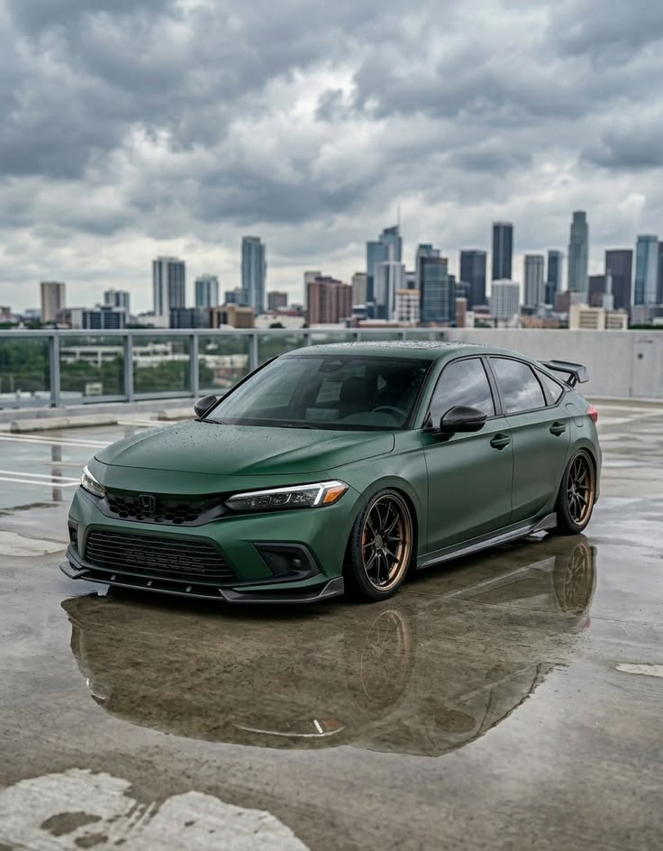 Modified green matte Honda Civic hatchback on wet rooftop with city skyline